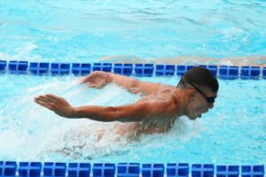 Plivač u delfin stilu između plutajućih linija staze